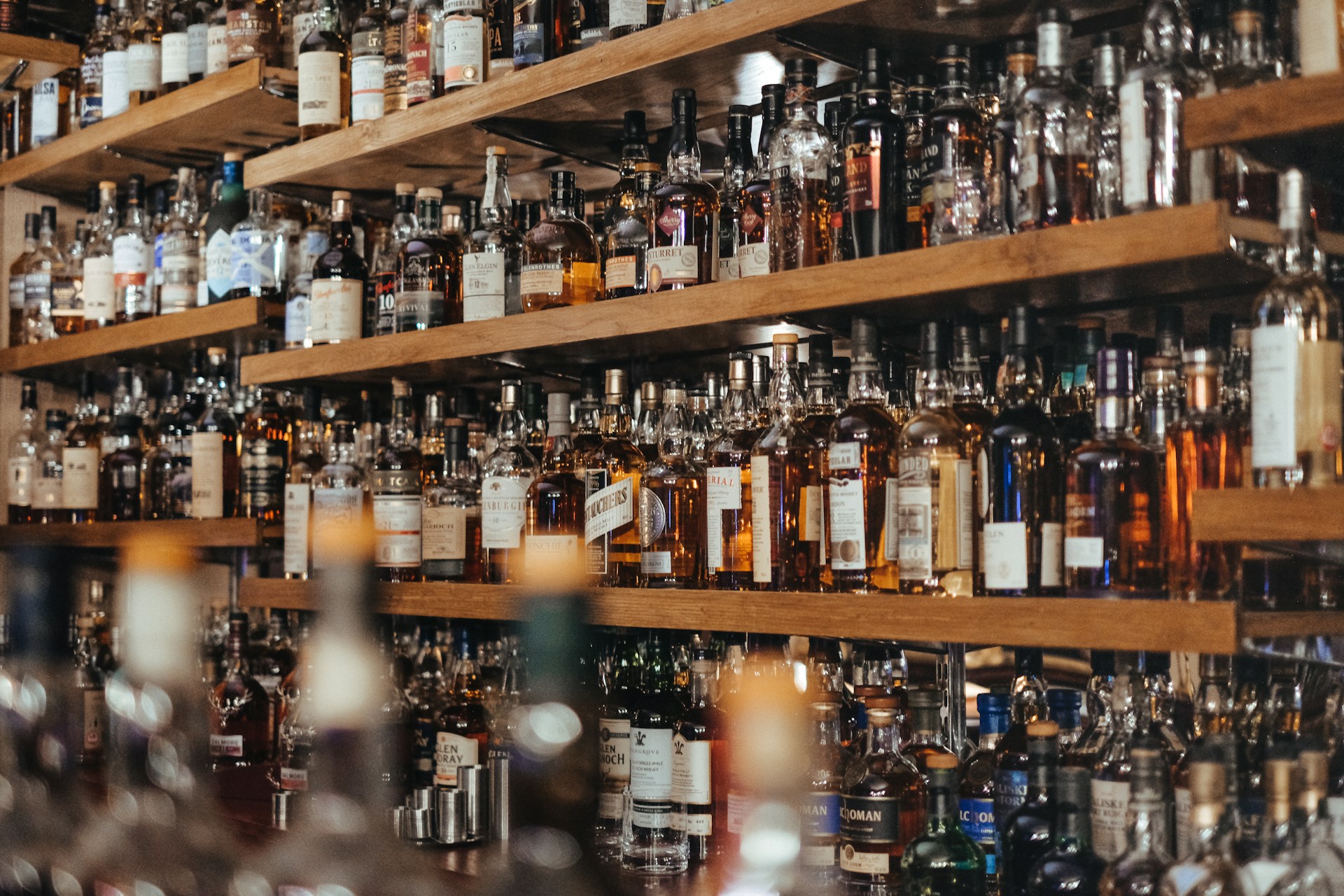 Assorted bottles of alcohol in different colors crowded on store shelves.